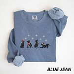 Blue Jean crewneck sweatshirt laid flat with a rolled cuff, embroidered with four black pitbull silhouettes in a Santa hat, striped scarves and a knit hat under snowflakes