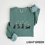 Light Green crewneck sweatshirt laid flat with a rolled cuff, embroidered with four black pitbull silhouettes in a Santa hat, striped scarves and a knit hat under snowflakes