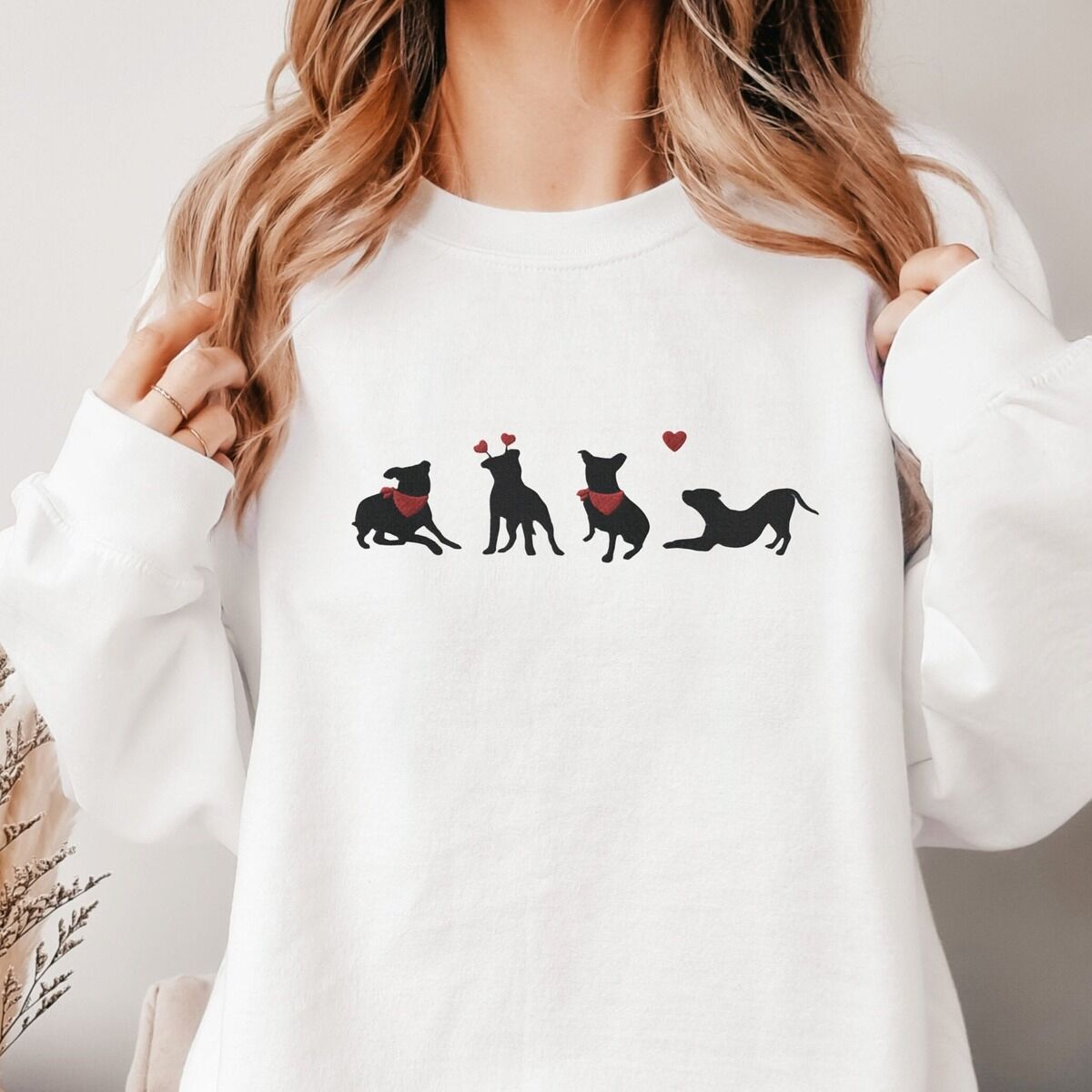 Pitbull Valentine Sweatshirt - worn Smiling woman in a White crewneck sweatshirt embroidered with four black pitbull silhouettes with red bandanas, a red heart headband and a floating red heart