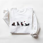 White crewneck sweatshirt laid flat, embroidered with four black pitbull silhouettes with red bandanas, a red heart headband and a floating red heart