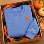 Heather Deep Royal poodle crewneck with the name Mochi on the sleeve in a gift box with orange tissue paper and pumpkins