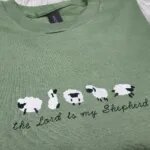Close-up of the embroidered sheep and the Lord is my Shepherd script in black thread