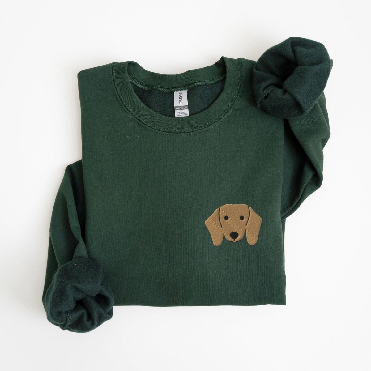 Red Dachshund Sweatshirt – Forest Green Forest Green crewneck sweatshirt laid flat on white, embroidered with a red dachshund face with long floppy ears, round black eyes and a little smile on the left chest
