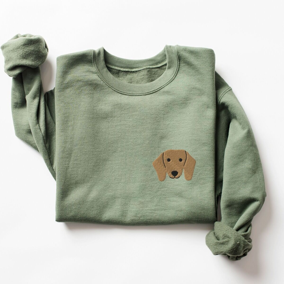 Red Dachshund Sweatshirt – Military Green Military Green crewneck sweatshirt laid flat on white, embroidered with a red dachshund face with long floppy ears, round black eyes and a little smile on the left chest