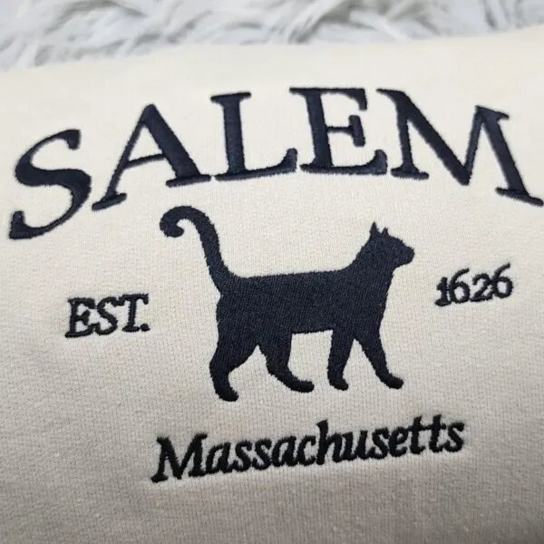 Close-up of the black Salem Massachusetts embroidery with arched SALEM letters over a walking black cat