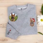 Grey sweatshirt with an embroidered shepherd mix portrait in a Santa hat and Love with a heart on the sleeve