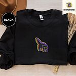 Black crewneck sweatshirt with a brown felt hat and dried bunny tail grass, embroidered with a startled black cat with an arched back, a puffed tail and yellow eyes, outlined in layered rainbow neon stitches
