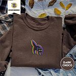 Dark Chocolate crewneck sweatshirt on a plaid flannel shirt with yellow autumn leaves and denim shorts, embroidered with a startled black cat with an arched back, a puffed tail and yellow eyes, outlined in layered rainbow neon stitches