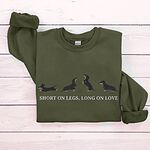 Military Green crewneck sweatshirt laid flat on white wood, embroidered with four black and tan dachshunds in a row above the words SHORT ON LEGS, LONG ON LOVE across the chest
