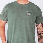 Man in a Bay T-shirt embroidered with a white goose and the words silly dada in a dark thread