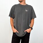 Man standing with his hands in his pockets in a Pepper T-shirt embroidered with a small white goose and the words silly dada