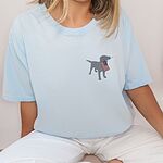 Woman sitting in a Chambray T-shirt with a small silver Labrador carrying a USA flag on the left chest