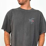 Man wearing a charcoal T-shirt with a silver lab silhouette carrying an American flag on the left chest