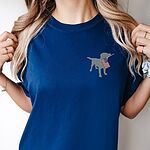 Woman in a deep blue T-shirt with a small silver Labrador holding a USA flag on the left chest