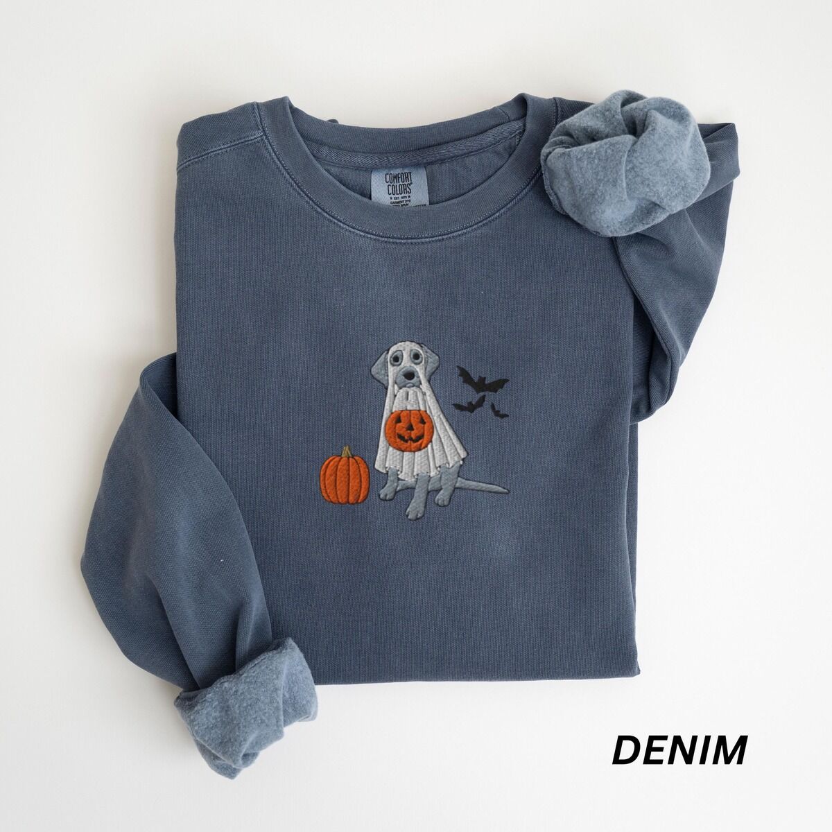 Silver Lab Ghost Sweatshirt – Denim Denim crewneck sweatshirt laid flat, embroidered with a silver-gray Labrador under a white ghost sheet holding a jack-o'-lantern bucket