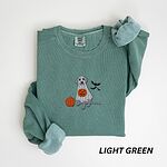 Light Green crewneck sweatshirt laid flat, embroidered with a silver lab trick-or-treating in a ghost sheet beside a pumpkin and bats