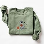 Military Green crewneck sweatshirt laid flat with rolled cuffs, embroidered with a silver Labrador in a white ghost sheet holding a jack-o'-lantern bucket beside a pumpkin and three bats