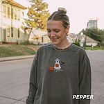 Woman on a street in a Pepper crewneck sweatshirt embroidered with a silver lab in a ghost costume holding a jack-o'-lantern bucket