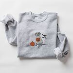 Sport Grey crewneck sweatshirt laid flat with rolled cuffs, embroidered with a silver lab trick-or-treating in a ghost sheet beside an orange pumpkin and bats