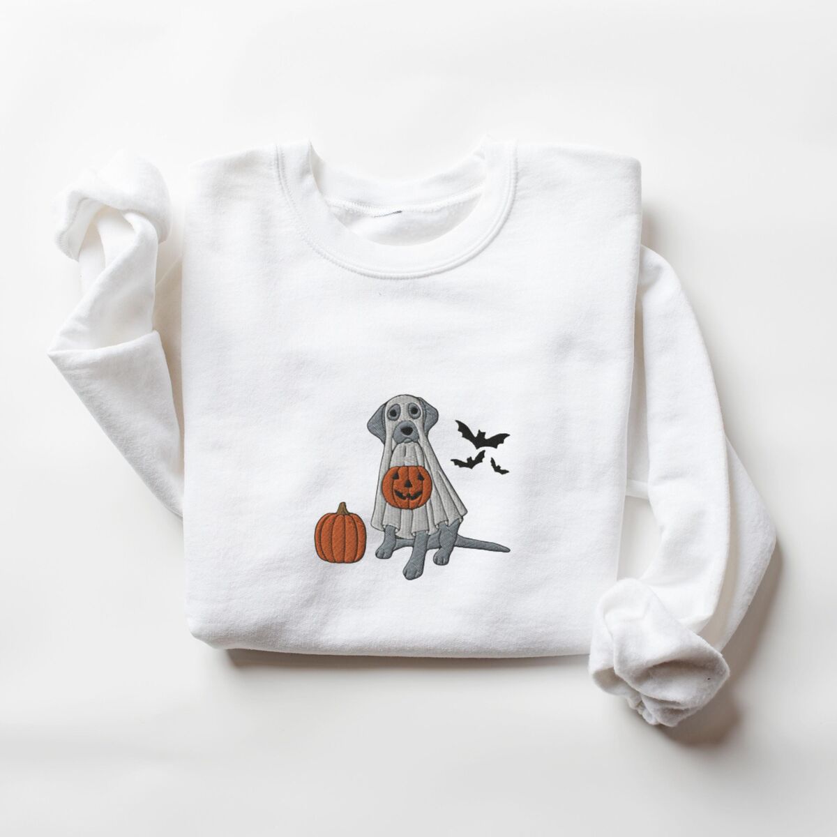 Silver Lab Ghost Sweatshirt - White White crewneck sweatshirt laid flat, embroidered with a silver Labrador in a ghost costume, an orange pumpkin and three black bats