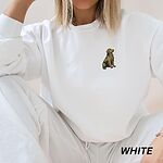 Woman sitting in a White crewneck sweatshirt and white pants, embroidered with a small sitting golden retriever on the left chest