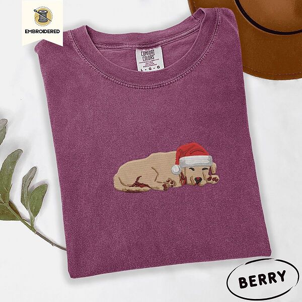 Berry Comfort Colors T-shirt embroidered with a golden retriever puppy napping with its head on its paws in a red Santa hat
