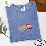 Blue Jean Comfort Colors T-shirt embroidered with a golden retriever puppy napping with its head on its paws in a red Santa hat