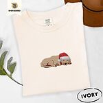 Ivory Comfort Colors T-shirt embroidered with a golden retriever puppy napping with its head on its paws in a red Santa hat