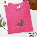 Crunchberry Comfort Colors T-shirt embroidered with a long-haired dachshund in a purple sweater and pom-pom beanie riding a snowboard