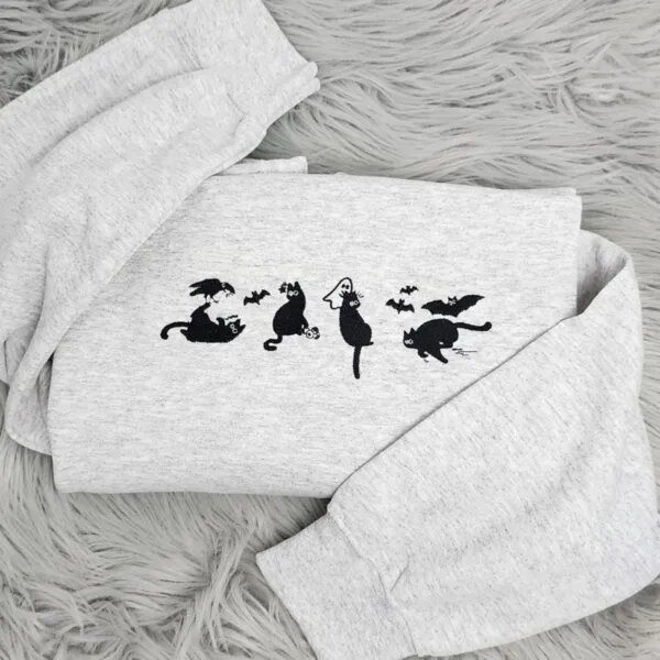 Spooky black cat sweatshirt in light heather grey with four embroidered black cats, a crow, bats and a tiny ghost across the chest