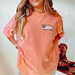Woman in a Terracotta T-shirt embroidered on the left chest with a long-haired dachshund in a ghost sheet carrying a jack-o'-lantern bucket
