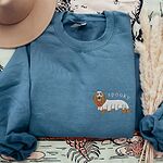 Indigo Blue crewneck sweatshirt laid flat with a felt hat, embroidered small on the left chest with a long-haired dachshund in a ghost sheet and the word spooky