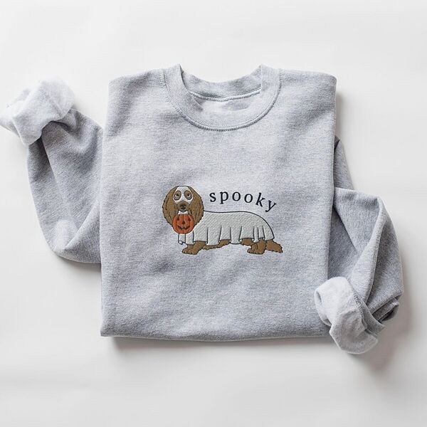 Sport Grey crewneck sweatshirt laid flat on white, embroidered in the center with a long-haired dachshund in a ghost sheet carrying a jack-o'-lantern bucket under the word spooky