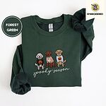 Forest Green crewneck sweatshirt folded on a white background, embroidered with a doodle, a chocolate lab and a golden retriever in Halloween sweaters above spooky season in script