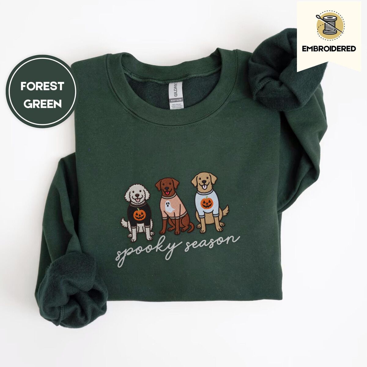 Spooky Pups Sweatshirt – Forest Green Forest Green crewneck sweatshirt folded on a white background, embroidered with a doodle, a chocolate lab and a golden retriever in Halloween sweaters above spooky season in script