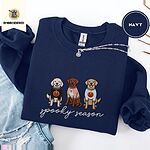 Navy crewneck sweatshirt folded with ripped jeans and a silver chain necklace, embroidered with a doodle, a chocolate lab and a golden retriever in Halloween sweaters above spooky season in script