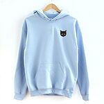 Light Blue pullover hoodie on a wooden hanger against a white wall, embroidered with a small tortoiseshell cat face, black with golden caramel patches, on the left chest