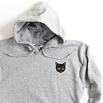 Close-up of a Sport Grey pullover hoodie with drawstrings, embroidered with a small tortoiseshell cat face, black with golden caramel patches, on the left chest