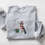 Sport Grey crewneck sweatshirt folded on a white background, embroidered with a black tri Australian shepherd in a Santa hat and red scarf with a green gift box and silver snowflakes