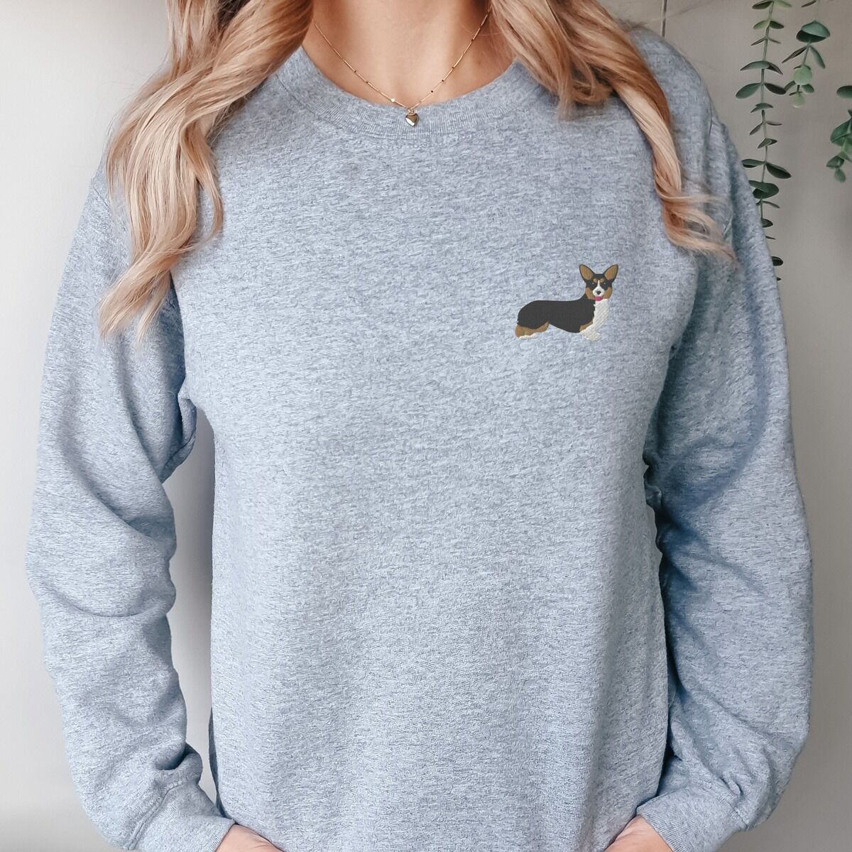 Tricolor Corgi Sweatshirt - worn in grey Woman in a Sport Grey crewneck sweatshirt embroidered with a black, tan and white corgi on the left chest