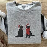Sport Grey crewneck sweatshirt laid flat on wood, embroidered with two black Labradors in Santa hats, one holding a candy cane and one in a red scarf
