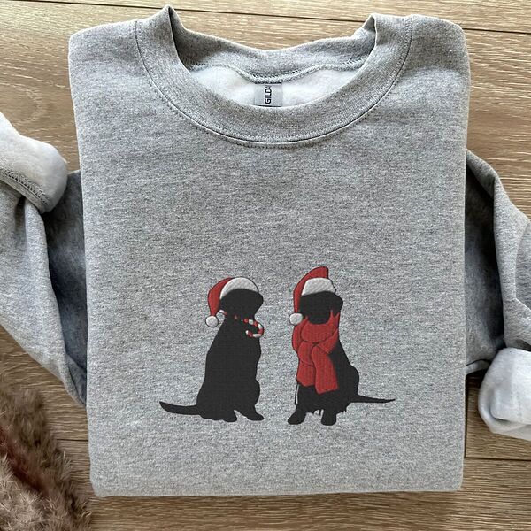 Sport Grey crewneck sweatshirt laid flat on wood, embroidered with two black Labradors in Santa hats, one holding a candy cane and one in a red scarf