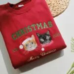 Two cats Christmas sweatshirt with green EST 2025 and gold Merry Christmas embroidery