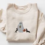 Sand crewneck sweatshirt laid flat on white, embroidered with a ghost sipping iced coffee between two black and tan dachshunds and a jack-o'-lantern pail