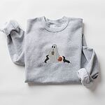 Sport Grey crewneck sweatshirt laid flat on white, embroidered with a ghost sipping iced coffee between two black and tan dachshunds and a jack-o'-lantern pail