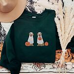 Forest Green crewneck sweatshirt laid flat with a brown hat and dried pampas, embroidered with two golden retrievers in white ghost sheets with a jack-o'-lantern, a pumpkin bucket and a small pumpkin