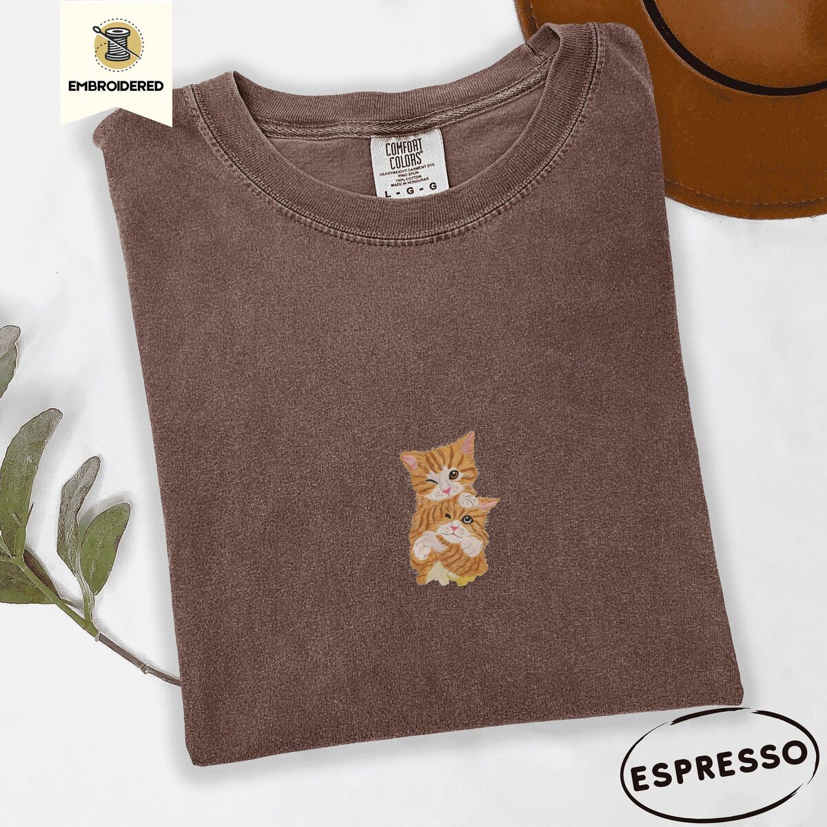 Two Kittens Shirt – Espresso Espresso Comfort Colors T-shirt embroidered with two orange tabby kittens, one winking with a paw on the other's head
