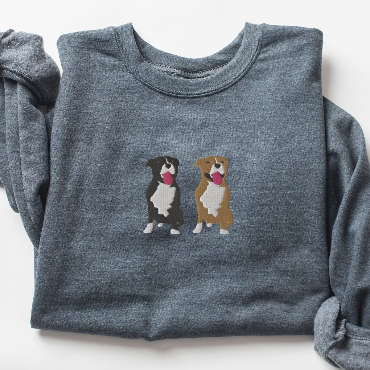 Two Pitbulls Sweatshirt – Dark Heather Dark Heather crewneck sweatshirt laid flat, embroidered with a black and white tuxedo pit bull and a fawn pit bull sitting side by side with their tongues out, centered on the chest