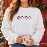 Woman in a white Christmas cow sweatshirt in front of a red barn door with a Christmas wreath