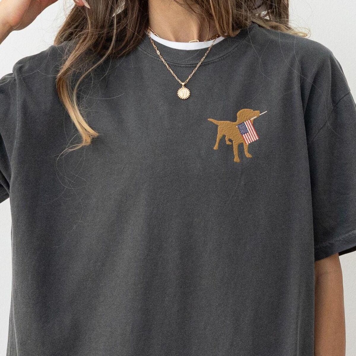 Yellow Lab American Flag Shirt – Pepper Woman in a Pepper T-shirt with a white tee underneath, a golden lab carrying a flag on the left chest